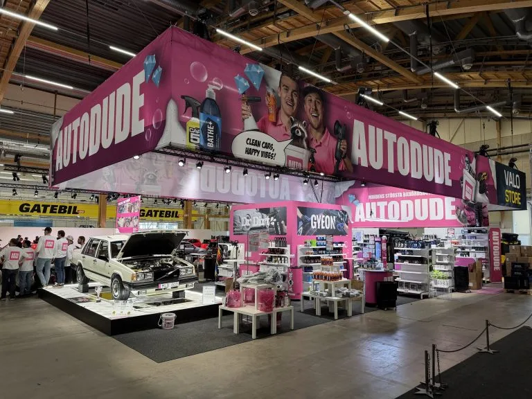 Autodudes rosa mässmonter på Elmia Custom Motor Show med takskylt och utställningsbil, byggd av Wilzéns Expo