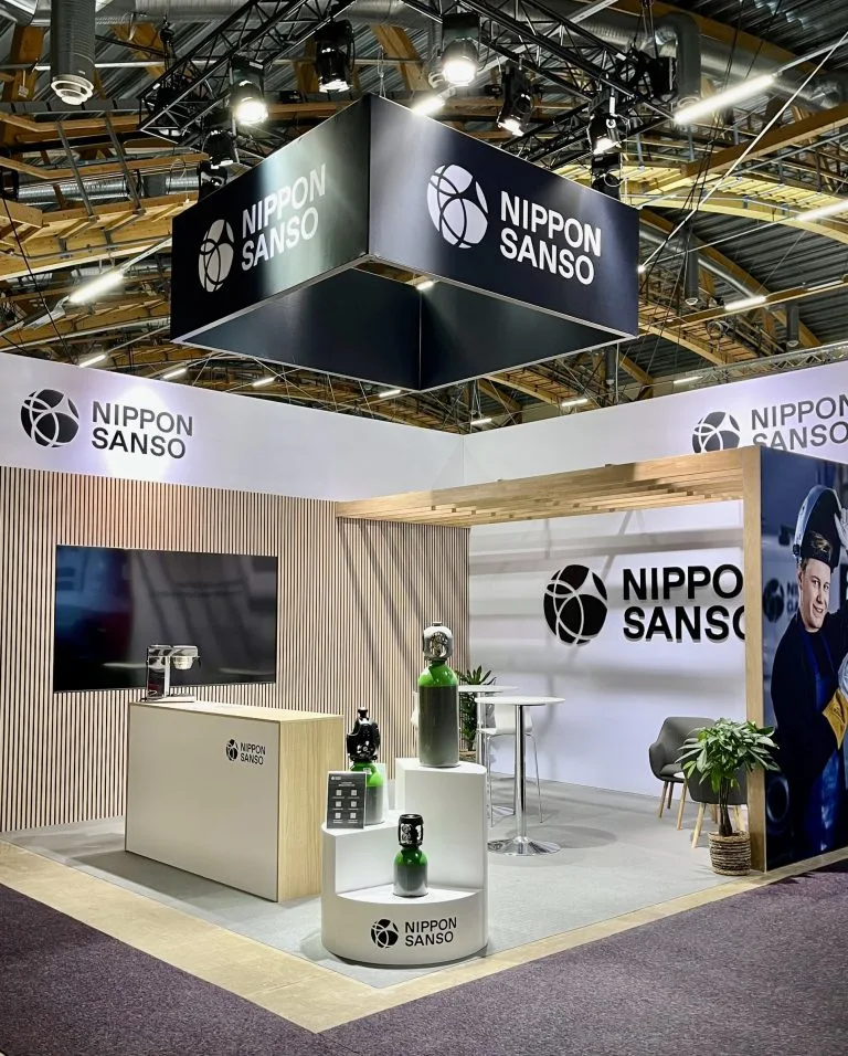 Nippon Sansos hörnmonter med ribbad träfasad och produktpodier, byggd av Wilzéns Expo