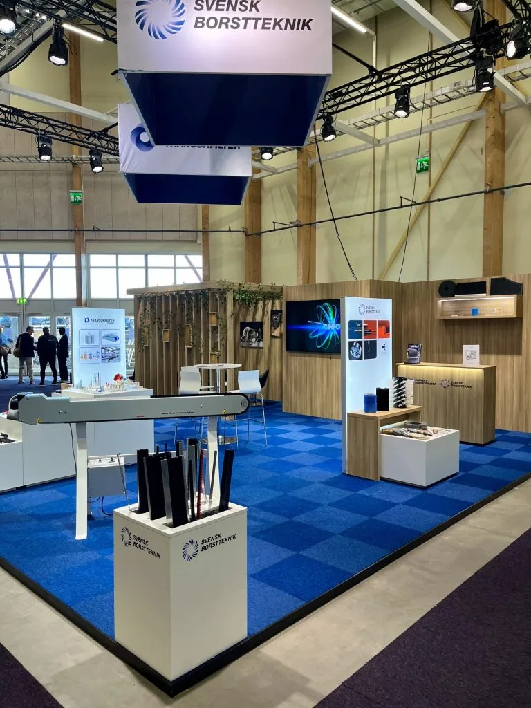Svensk Borstteknik mässmonter med träklädd vägg och rund takskylt, byggd av Wilzéns Expo